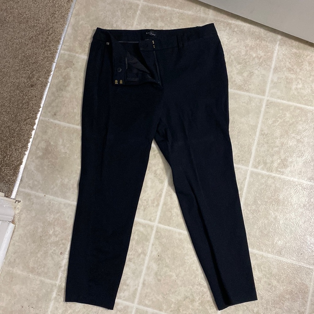 Slacks, black, with some creases from folding and a bit of wear on the hems.